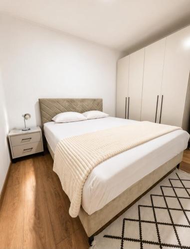 a bedroom with a large bed with white cabinets at Apartment Arma in Mostar