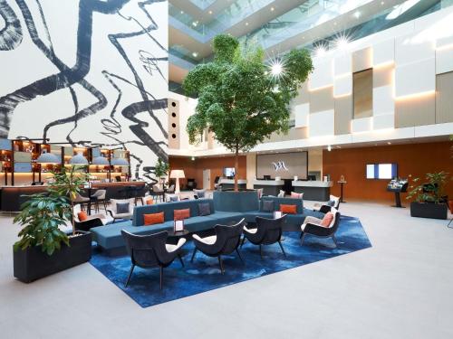 a lobby with chairs and tables in a building at Mercure Geneva Airport in Geneva