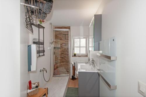 a white bathroom with a sink and a shower at Ferienwohnung im Strumpfweberhaus in Schiltach