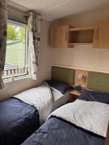 two beds in a small room with a window at 10 the green lilliardsedge carvan park harritsfield jedbrugh td8 6tz in Harrietsfield
