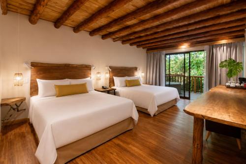 two beds in a room with wooden ceilings at La Aldea De La Selva Lodge in Puerto Iguazú