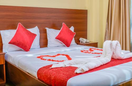 a bed with red pillows and a heart made out of towels at Delfirm Hotel in Nairobi