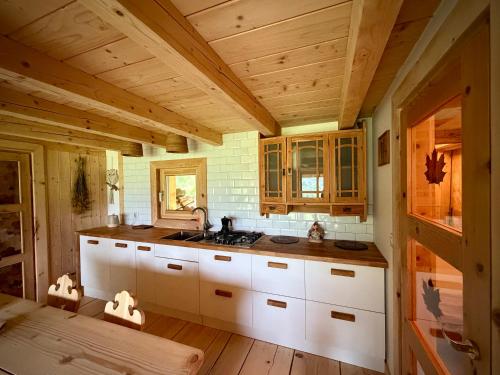 a kitchen with white cabinets and a wooden ceiling at Górska Osada Berdo in Chmiel
