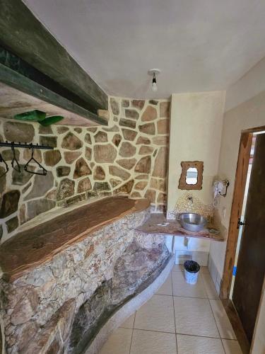a stone bathroom with a sink and a stone wall at Canto Verde Pousada in Lençóis
