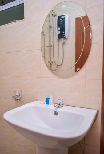 a white sink in a bathroom with a mirror at Delfirm Hotel in Nairobi