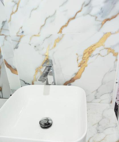 a white toilet in a bathroom with a marble wall at Paragone Home Stay Modern 3BR Apartment Style Home AC 5 Min to Enderamulla Station 15 Minute Train Ride to Colombo in Wattala