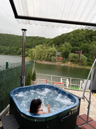 a woman in a jacuzzi tub next to a lake at Leo Green House in Cinciş