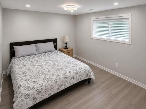 a white bedroom with a bed and a window at Newly Renovated 2BR Walkout Suite in the Heart of Kanata Ottawa in Ottawa