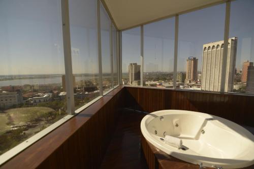 a bath tub in a room with large windows at Hotel Guarani Asuncion in Asunción