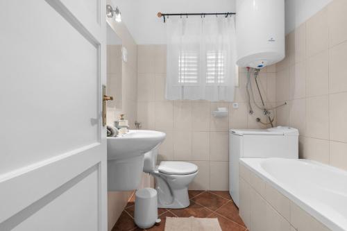 a white bathroom with a toilet and a sink at Gery Apartman in Zamárdi