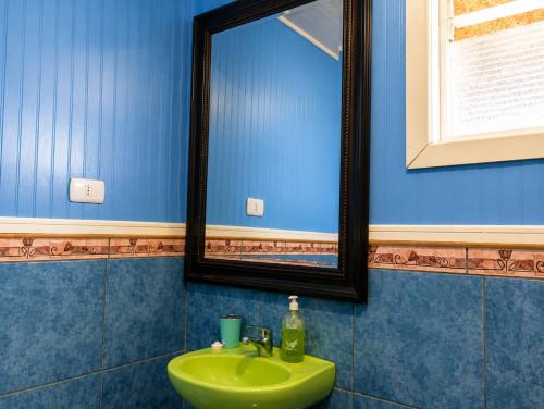 a bathroom with a green sink and a mirror at El Urco Chiloé - Hostal y Cabaña in Ancud