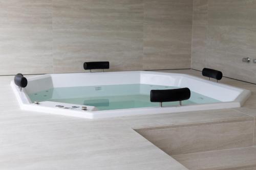 a bath tub with two black chairs in a room at Loft completo no Centro de Itaipava in Araras Petropolis