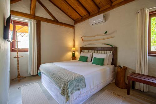 a bedroom with a white bed with green pillows at Casa Caroá - Chalé 2 in Japaratinga