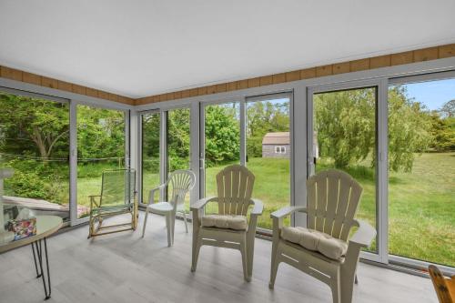 a screened in porch with three chairs and a table at Relaxing Barnstable Getaway Close to the Beach in Barnstable