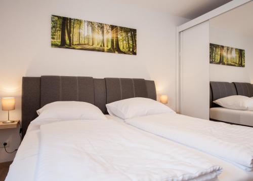 2 Betten in einem Schlafzimmer mit weißer Bettwäsche in der Unterkunft Ferienwohnung Kappenblick 1 - Buchenweg in Winterberg