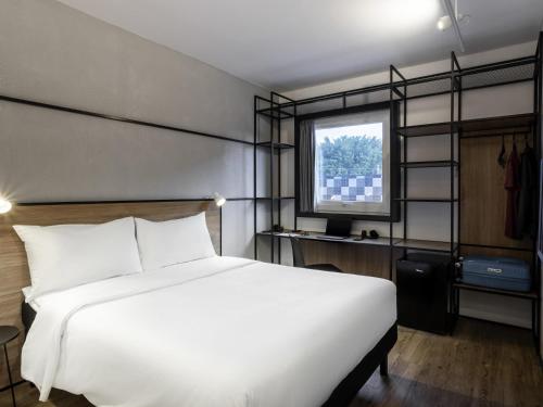 a bedroom with a large white bed and a window at ibis Botucatu in Botucatu