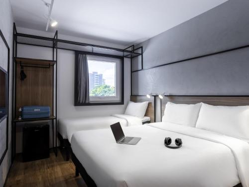 a hotel room with two beds and a laptop on the bed at ibis Botucatu in Botucatu