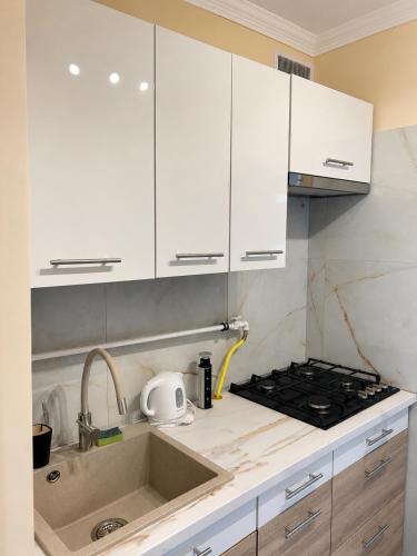 a kitchen with white cabinets and a sink at Harmónia Home in Miskolc