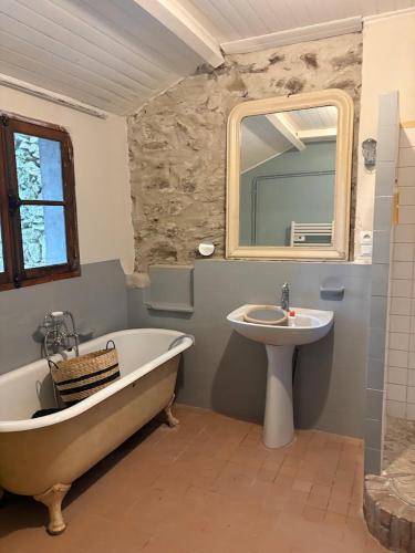 a bathroom with a tub and a sink and a mirror at Cottage LAISSER VERDURE in Gargilesse-Dampierre