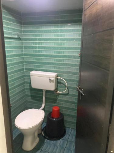 a bathroom with a toilet and green tiled walls at sree thilak apartments in Guruvāyūr