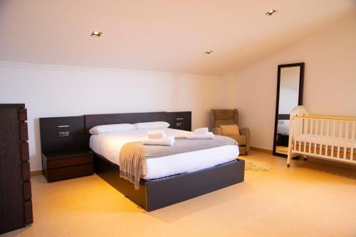a bedroom with a bed and a mirror and a crib at Welcome Villa O Sidrón in Alba