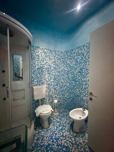a blue tiled bathroom with a toilet and a sink at Diaz 10 Suite in Trieste
