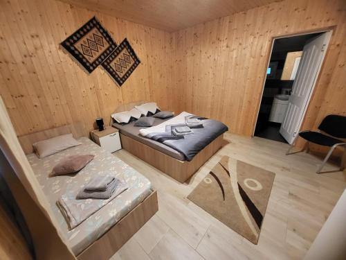 two beds in a room with wooden walls and wooden floors at Casa Claudiu in Eşelniţa