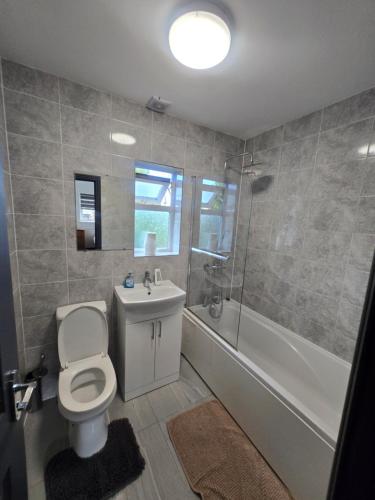 a bathroom with a toilet and a tub and a sink at White Shelf Dartford House in Kent