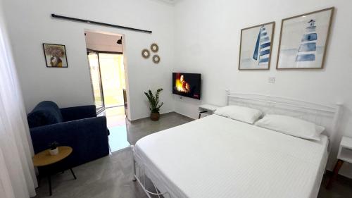 a bedroom with a white bed and a couch and a tv at Salamina Urban Escape C in Paloúkia