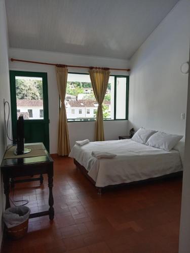 a bedroom with a bed and a table and windows at Hotel Turístico de Tenza in Tenza