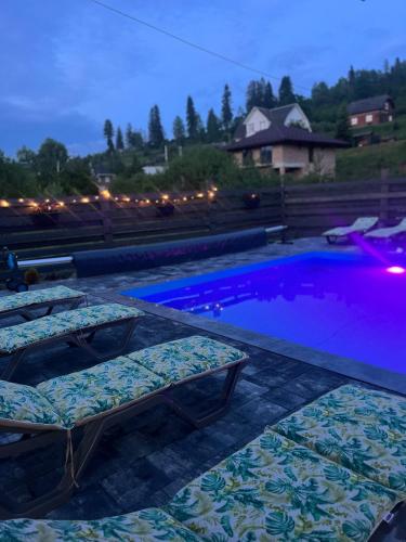 a swimming pool with two lounge chairs next to it at котедж петриківка З червня басейн з підігрівом 10 на 5 метрів in Slavske
