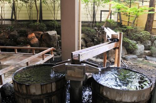 a water fountain in a garden with two barrels at Shima Grand Hotel in Nakanojo
