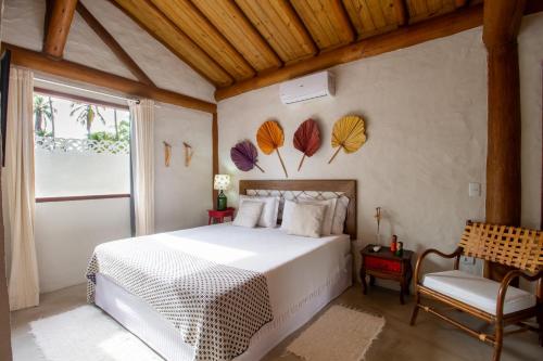 a bedroom with a white bed with leaves on the wall at Casa Caroá - Chalé 3 in Japaratinga