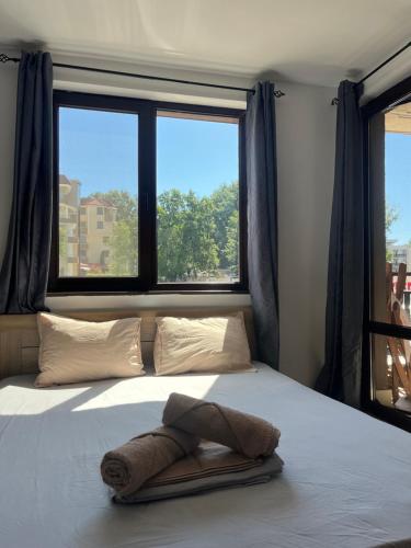 a bed with a towel on it in front of a window at Atliman Beach Apartment 1 in Kiten