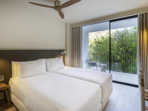 a bedroom with a large white bed and a balcony at Mercure Benidorm in Benidorm
