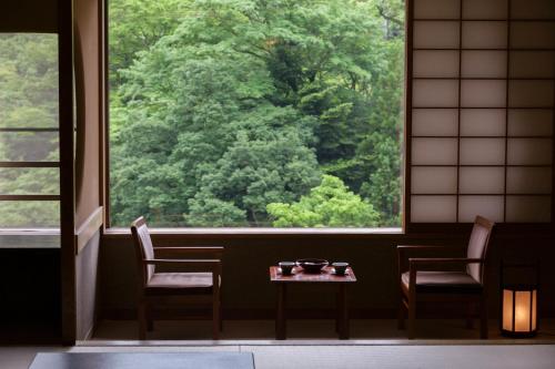 a room with a table and two chairs and a large window at Shima Grand Hotel in Nakanojo