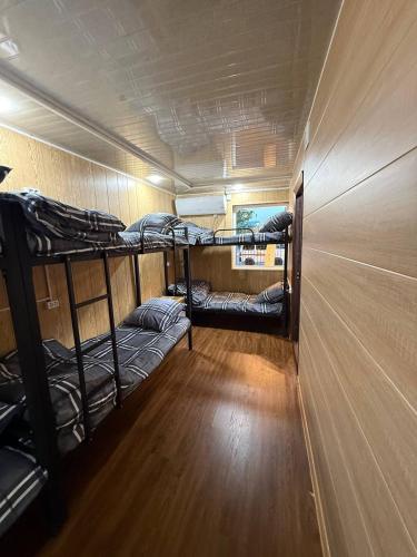 a room with three bunk beds and a wooden floor at Noor house hostel in Fergana