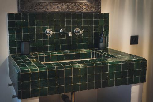 a green tiled bathroom with a green sink at Maison Vitis in Fuissé