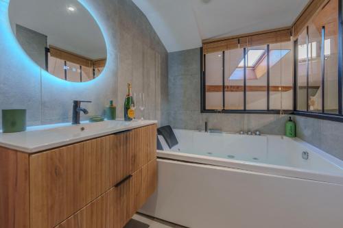 a bathroom with a tub and a sink and a mirror at La grande Sure & Spa in Voiron