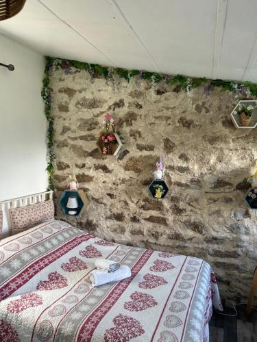 a bedroom with a stone wall with a bed at Le rêve chrysalide in Masseret