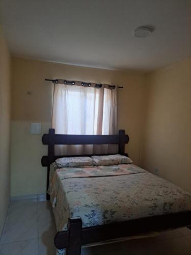 a bedroom with a bed and a window with a curtain at Kitnet Praia de Alagoinhas in Fortaleza