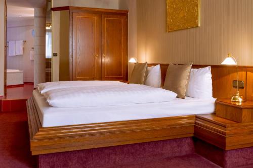 a bedroom with a large bed with a wooden headboard at Schwarzer Bär Jena in Jena