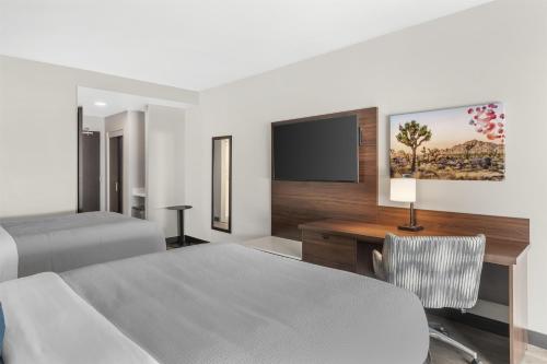 a bedroom with a bed and a desk and a tv at Best Western Plus Rialto in Rialto