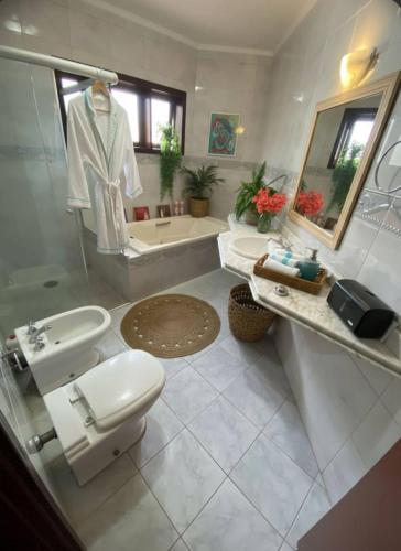 a bathroom with a toilet and a sink and a tub at Suíte Aconchegante com Hidromassagem Jardim Esplanada in São José dos Campos