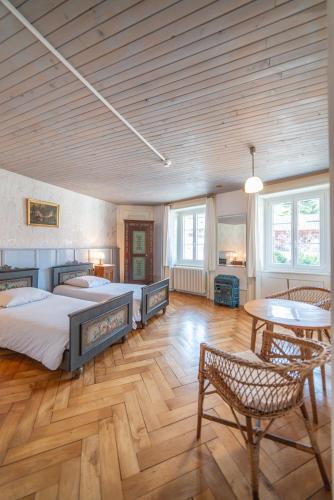 a bedroom with two beds and a table in it at Hôtel Von Bergen in La Sagne