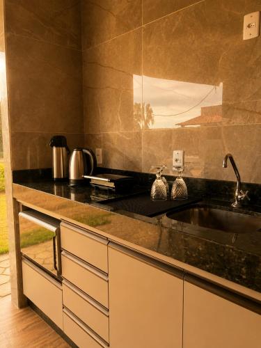 a kitchen with a black counter and a sink at Flats Araras do Vale in Colinas Do Sul