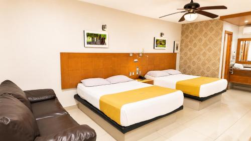 a hotel room with two beds and a couch at Hotel Maioris El Diez Culiacan in Culiacán