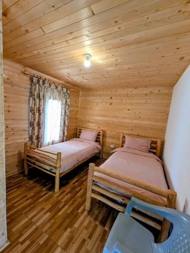 two beds in a room with wooden walls at Guests house, Artani in Valbonë