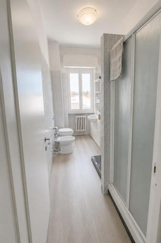 a white bathroom with a toilet and a window at Alessandro home in Rozzano