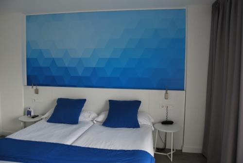 a bed with two blue pillows in a bedroom at Estudiotel Alicante in Alicante